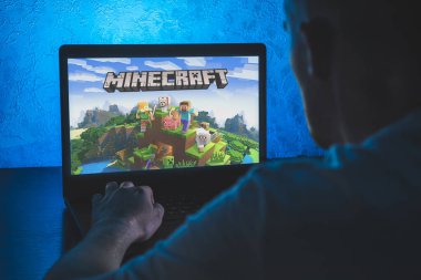 Minecraft bir kum havuzu video oyunudur. Bilgisayar oyunu. Adam dizüstü bilgisayarda video oyunu oynuyor