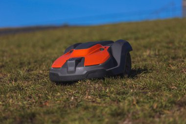 Otomatik çim robotu, parlak mavi gökyüzünün altındaki yemyeşil bir bahçeyi sessizce buduyor. Yüksek kalite fotoğraf