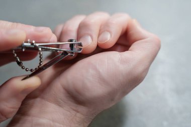 Close-up of a person carefully trimming fingernails using a metal nail clipper at home, highlighting personal grooming and hygiene on a neutral background. High quality photo