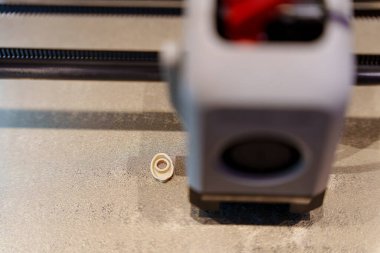 Bir 3D yazıcının yukarıdan aşağı görüntüsü, yazdırma yatağının üzerinde hareket eden yazıcı başlığını açıkça gösteriyor, makinenin içinde bağlı kablolar ve aydınlatma ile. Yüksek kalite fotoğraf