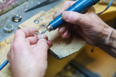 Kuyumcu ahşap tezgahta gümüş bir yüzüğü parlatmak için döner bir alet kullanıyor. Yüksek kalite fotoğraf