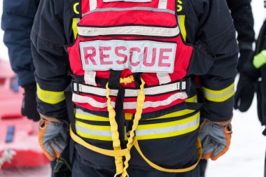 Kurtarma görevlisinin acil durum operasyonu sırasında kırmızı güvenlik yeleği ve emniyet kemeriyle arka görüntüsü. Yüksek kalite fotoğraf