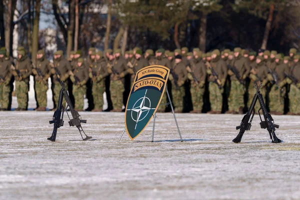 NATO Savaş Grubu kalkanı ve tüfekleri arka planda askerlerle birlikte sahada sergileniyor. Yüksek kalite fotoğraf