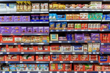 Bisküvi, kurabiye ve paketlenmiş atıştırmalıklarla dolu bir süpermarkette raflar. Yüksek kalite fotoğraf