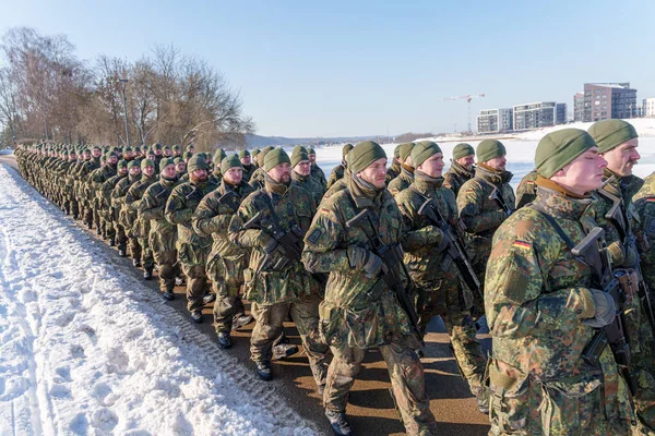 Kamuflaj üniformalı Alman askerleri askeri tatbikat sırasında karlı bir yolda formasyon halinde yürüyorlar. Yüksek kalite fotoğraf
