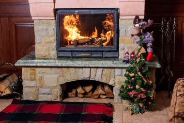 Yılbaşı ağacı ve şöminenin üzerinde renkli süslemeler var..