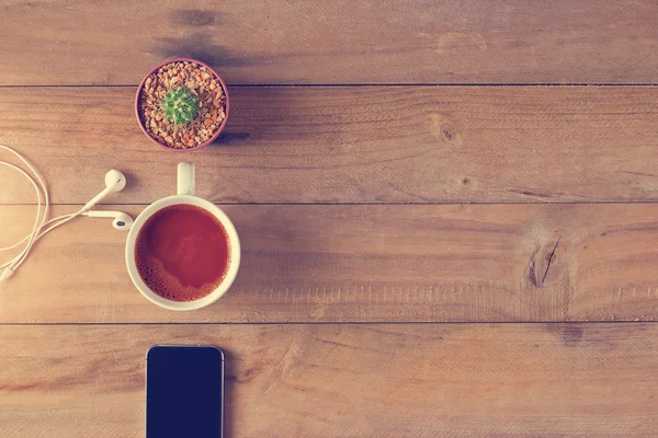 Bovenaanzicht van koffie, mobiele telefoon en cactus op een houten achtergrond — Stockfoto