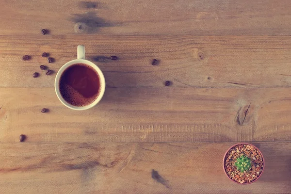 Xícara de café e cacto em vaso em madeira, vista superior — Fotografia de Stock