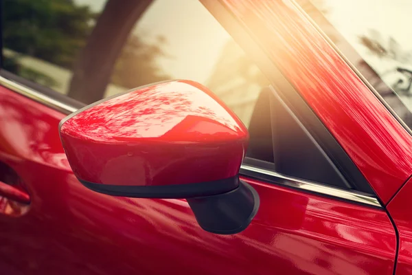 Zijde-achteruitkijkspiegel van de rode auto op straat achtergrond — Stockfoto