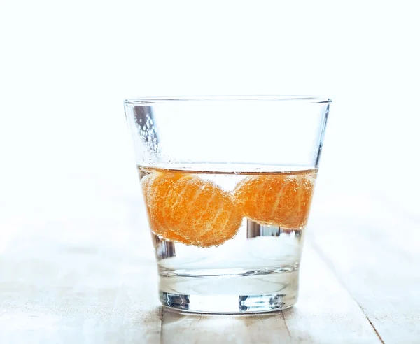Вода из апельсинов в стакане на деревянном фоне — стоковое фото