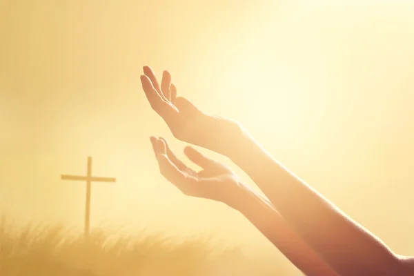 Respetar y rezar en la cruz y la naturaleza puesta del sol de fondo — Foto de Stock