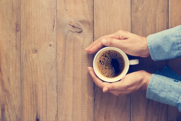 Mani di donna che tengono la tazza di caffè su sfondo di legno, Vista dall'alto, Tono vintage — Foto Stock