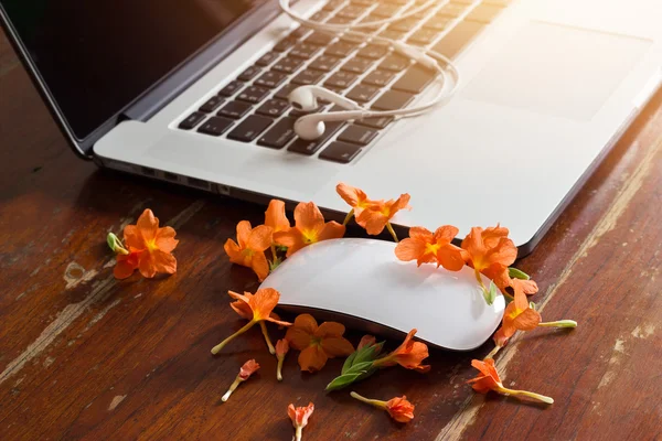 노트북, 이어폰 및 오래 된 나무 테이블 배경 꽃 — 스톡 사진