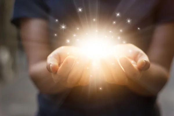 Stardust e magia em mãos de mulher no fundo escuro — Fotografia de Stock