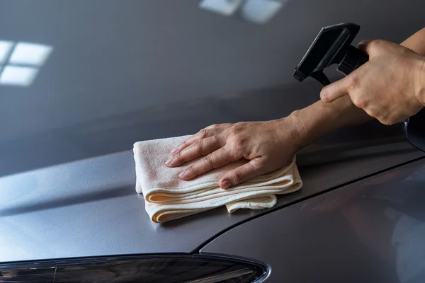 Woman cleaning car with microfiber cloth and cleaning spray — Stock Photo, Image