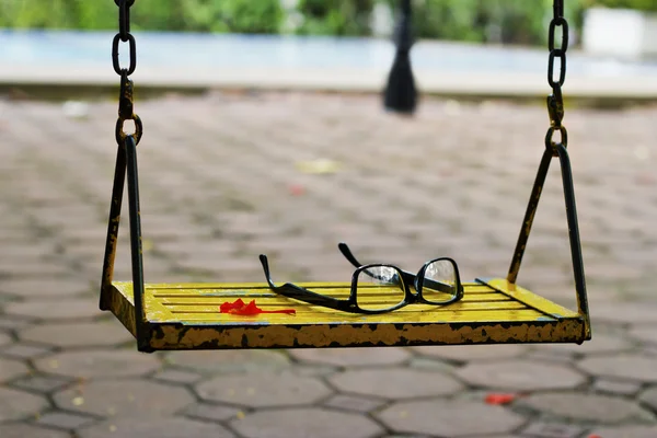 Gafas en el columpio en un parque y piscina —  Fotos de Stock