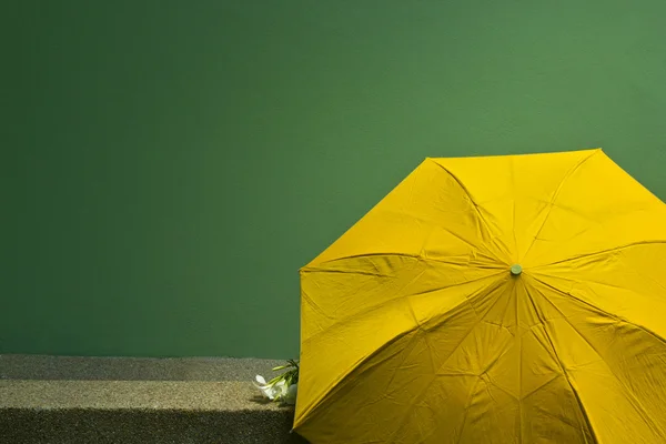 Alte gelbe Regenschirm auf der grünen Zementwand Hintergrund. — Stockfoto