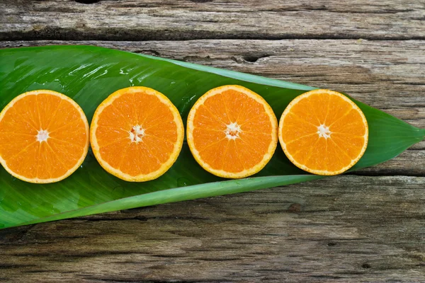 Orangenfruchtscheiben auf Blatt und Holzhintergrund, Naturkonzept — Stockfoto