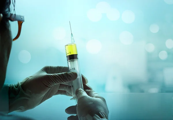 Syringe in hand glove on blue lab medical background — Stock Photo, Image