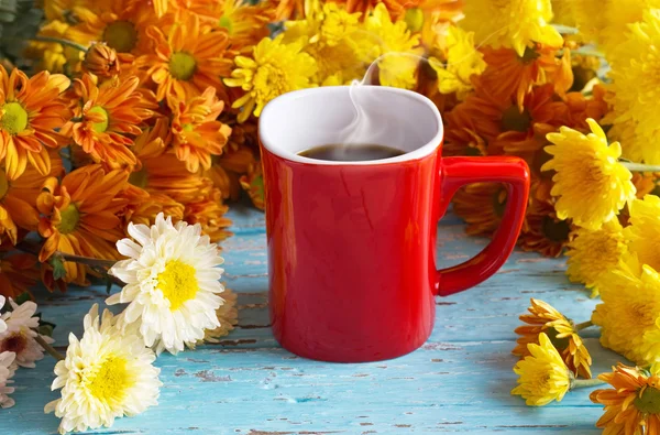 Café em copo vermelho e flores coloridas em fundo de madeira vibrante — Fotografia de Stock