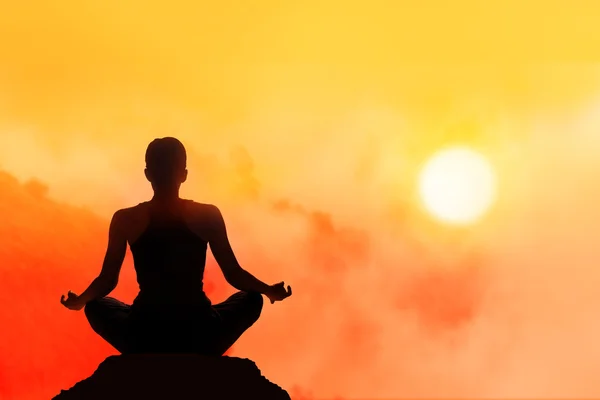 Kobiet medytuje na wysokim imponować w tle zachodu słońca — Zdjęcie stockowe