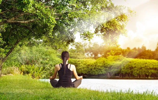 Sport woman meditating in nature green park at the sunrise — Stock Photo, Image