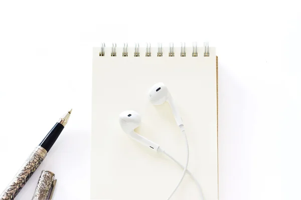 Kopfhörer auf Notizblock mit Stift auf weißem Hintergrund — Stockfoto