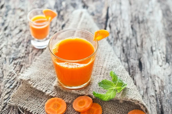 Frischer Karottensaft auf Sack und Holz — Stockfoto