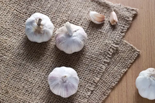 Garlics no saco e fundo de madeira — Fotografia de Stock