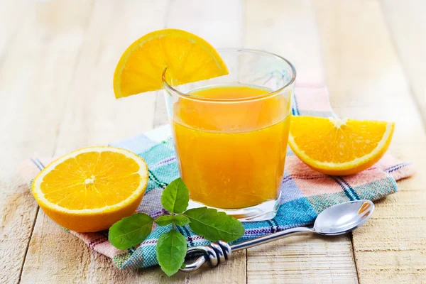 Glas av färska apelsiner juice med mynta på tyg och trä bakgrund — Stockfoto