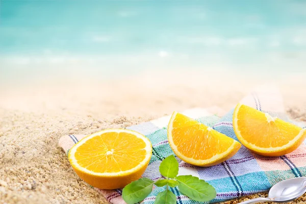 Färsk apelsin segment skiva med mynta på tyg och sand stranden sommardag — Stockfoto