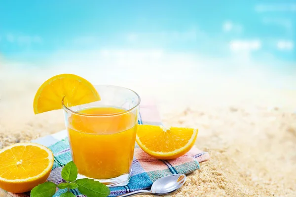 Sumo de laranja fresco com hortelã sobre tecido em vidro na areia praia mar verão dia — Fotografia de Stock