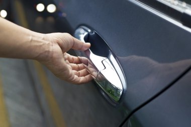 Adam sokakta bir arabanın kapısını açarak üzerindeki kolu, el