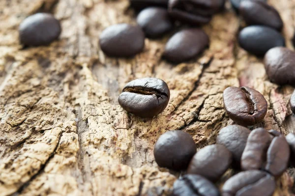 Granos de café sobre el fondo de madera viejo, tono cálido y enfoque suave — Foto de Stock