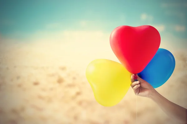 Vintage color tone balloon heart shpe in hand on sea sand beach — Stock Photo, Image