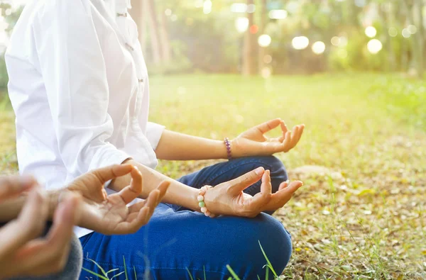 Women meditating outdoors in green park, warm color tone — 스톡 사진