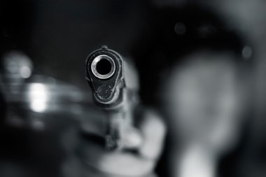 Black and white, woman pointing the old gun to front with one hand on dark background clipart