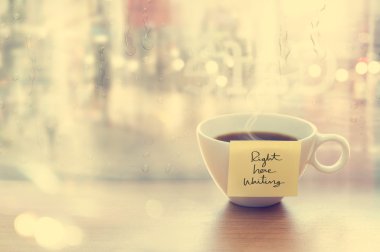 Steaming coffee cup with emotion message in coffee shop, front of mirror drop of rain