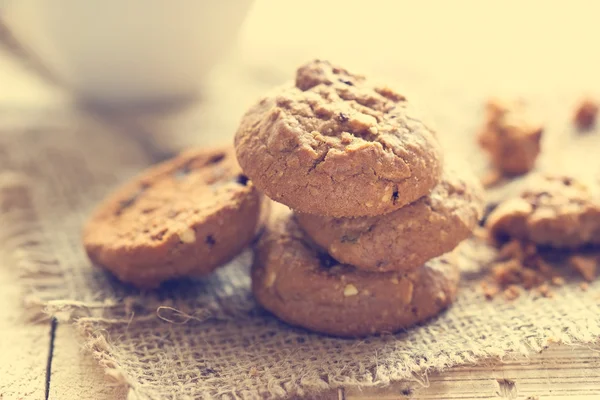 Galletas de chispas de chocolate en el saco encima de la mesa de madera, tono de color Vintage —  Fotos de Stock