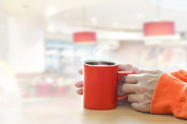 Red coffee cup with smoke in woman hand in coffee shop — Stock Photo, Image