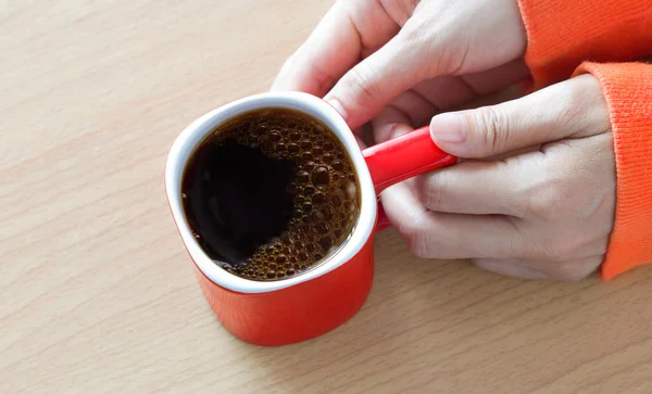 Tazza di caffè rosso con fumo nella mano della donna sul tavolo di legno — Foto Stock