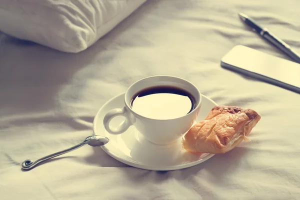 Xícara de café e torta de manhã no fundo da cama, tom de cor vintage — Fotografia de Stock