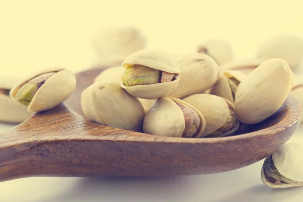 Heap salted pistachio nuts on wooden spoon background — Stock Photo, Image