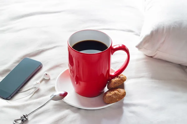 Красная кружка кофе и кулинария по утрам на фоне кровати — стоковое фото