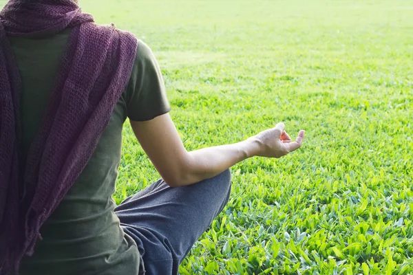 Mulher de ioga meditando ao ar livre no parque no fundo do campo de grama, foco na mão — Fotografia de Stock