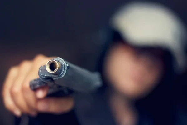 Kvinna som riktade en pistol mot målet på mörk bakgrund, selektiv — Stockfoto