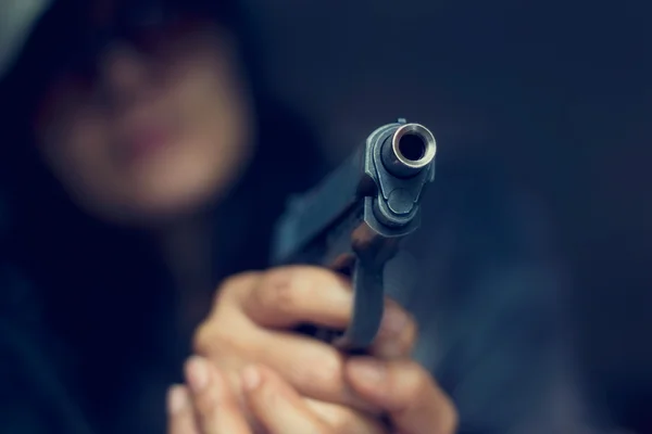 Koyu arka plan, seçici hedefinde silahı işaret kadın — Stok fotoğraf