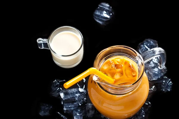 Thai ice tea in glass jar with milk and ice on black background — Stock Photo, Image