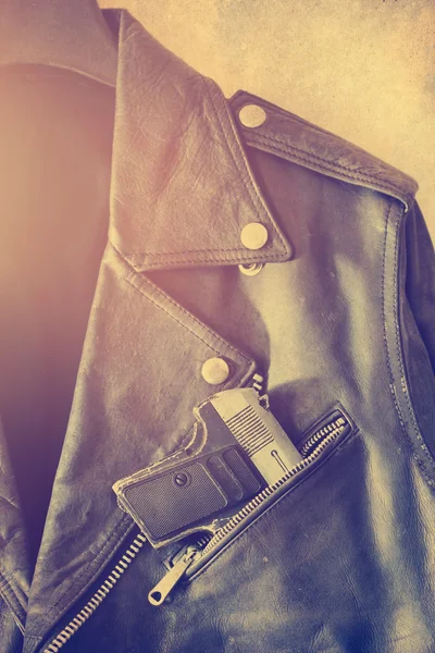 Jaqueta de couro antigo vintage com arma no bolso em fundo de papel de grão — Fotografia de Stock
