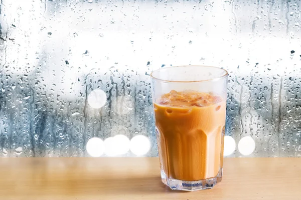 Tè al latte freddo su legno e gocce di pioggia su sfondo specchio — Foto Stock